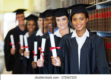 group of happy graduates holding diploma in library
