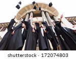 group of happy graduates throwing graduation hats in the air celebrating