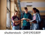 Group of happy high school students learning in a hallway. Copy space. 