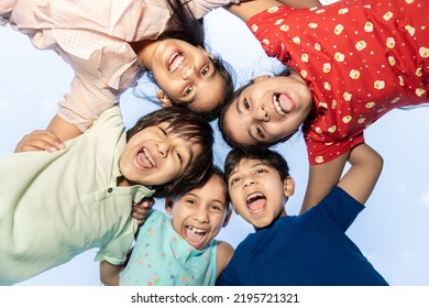 Group of happy Indian kids in circle looking down and embracing playing outdoor, Playful asian children together, looking at camera. Summer season background.  - Shutterstock ID 2195721321