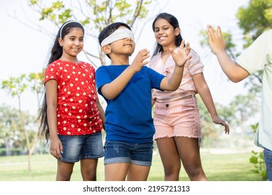 Group Of Happy Indian Kids Playing Blindfold Game Outdoors In Park, Playful Asian Children In The Garden.