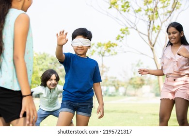 Group Of Happy Indian Kids Playing Blindfold Game Outdoors In Park, Playful Asian Children In The Garden.