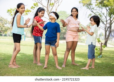 Group Of Happy Indian Kids Playing Blindfold Game Outdoors In Park, Playful Asian Children In The Garden.