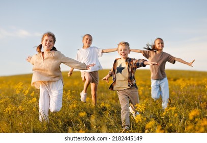Group of happy joyful school kids   running with outstretched arms in field on sunny spring day, excited children   boys and girls enjoying summer holidays in countryside - Shutterstock ID 2182445149