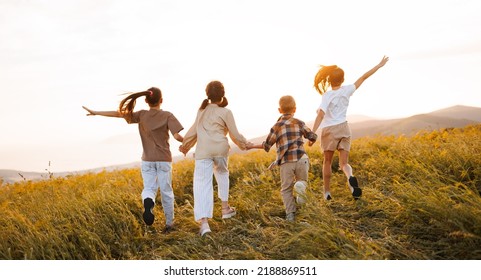 Group Of Happy Joyful School Kids   Running With Their Backs In Field On Sunny Spring Day, Excited Children   Boys And Girls Enjoying Summer Holidays In Countryside