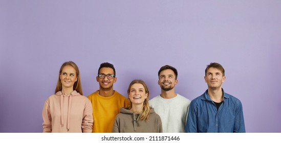 Group of happy joyful smiling young multiethnic Caucasian and mixed race Indian African people wearing hoodies and sweatshirts standing on purple background, looking up, thinking about something good - Powered by Shutterstock