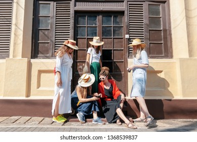 A group of happy joyful young stylish girls are traveling together, in hats against the background of a colonial house. Cuba