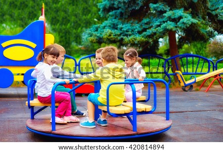 group of happy kids having fun on roundabout at playground