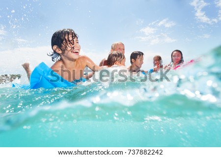 Group of happy kids play in the sea on matrass