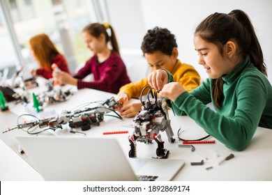 Group Of Happy Kids Programming Electric Toys And Robots At Robotics Classroom