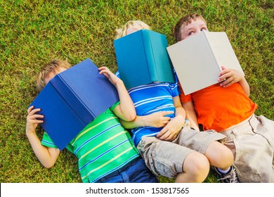 Group Of Happy Kids Reading Books Outside, Friendship And Learning Concept