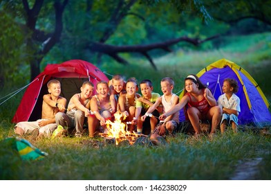 Group Of Happy Kids Roasting Marshmallows On Campfire