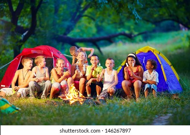 Group Of Happy Kids Roasting Marshmallows On Camp Fire