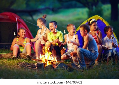 Group Of Happy Kids Roasting Marshmallows On Campfire