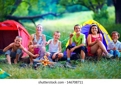 Group Of Happy Kids Roasting Marshmallows On Campfire