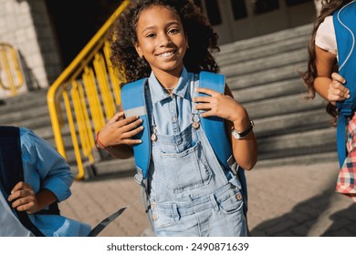 Group of happy kids schoolmates elementary middle school pupils with rucksacks backpack walking at school yard running out outside at the end of the lessons Education concept - Powered by Shutterstock