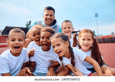 Group of happy kids and their PE teacher during sports training at the stadium. - Powered by Shutterstock