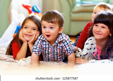 group of happy kids watching tv at home