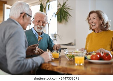 Group of happy mature friends talking while having a meal at dining table.	 - Powered by Shutterstock