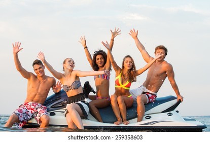 Group Of Happy Multi Ethnic Friends Sitting On A Jet Ski