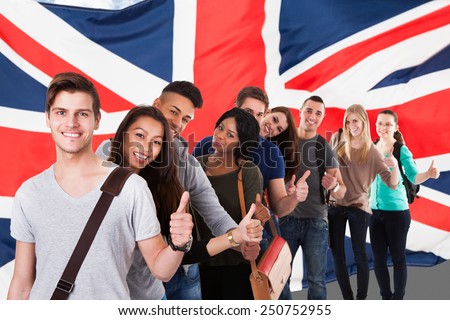 Group Of Happy Multi Ethnic Students Standing In Front Of Uk Flag Showing Thumb Up