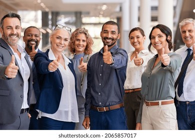 Group of happy multiethnic business people showing sign of success. Successful business team showing thumbs up and looking at camera. Portrait of smiling businessmen and businesswomen cheering. - Powered by Shutterstock