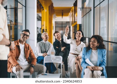 Group of happy multiethnic colleagues in casual clothes smiling and gesturing while having conversation about marketing strategy during meeting at work together on modern office - Powered by Shutterstock