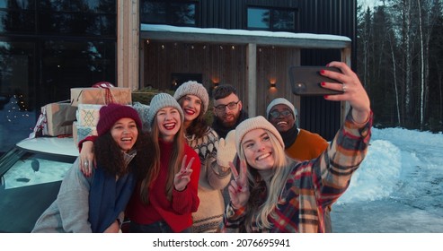 Group of happy multiethnic friends smile taking selfie pictures at snowy Christmas chalet house terrace slow motion. - Powered by Shutterstock