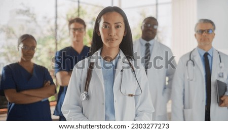 Group of Happy Multiethnic Team of Female and Male Doctors, Nurses and Healthcare Professionals Posing for Camera and Smiling. Portrait of a Confident Asian Physician Standing First in Focus