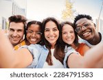 Group of happy multiracial teenagers having fun smiling taking a selfie portrait together on a students meeting. Five multiethnic young friends laughing and taking a photo with a smartphone. High