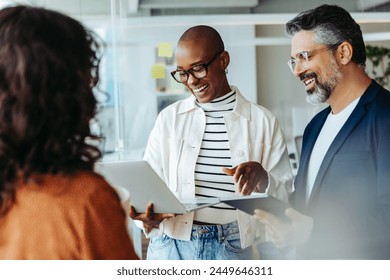 Group of happy people in business attire engaged in a conversation in their office. They are discussing and sharing ideas for their project, showing teamwork and cooperation. - Powered by Shutterstock