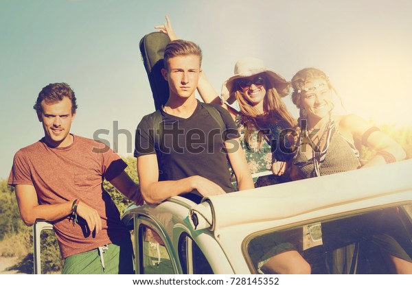 Group of happy people in a car in summertime\
ready for a road-trip.