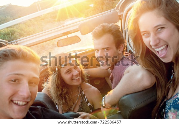 Group of\
happy people in a car at sunset in\
summer.