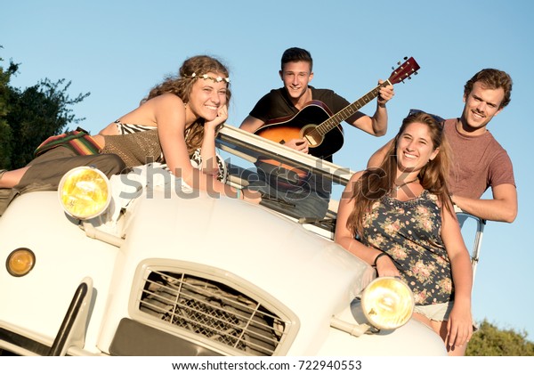 Group of\
happy people in a car at sunset in\
summer.