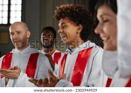 Group of happy people from church choir singing and clapping hands during performance
