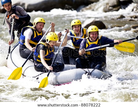 Group of happy people with guide whitewater rafting and rowing on river