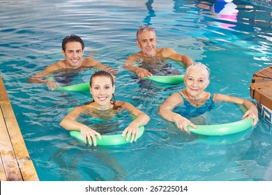 Group of happy people with swim noodles doing aqua fitness class in swimming pool
