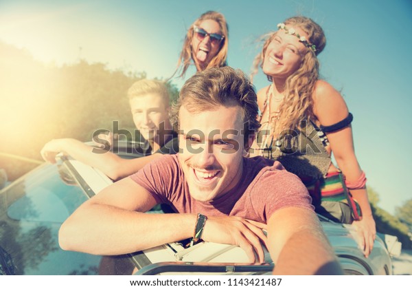 Group of happy people taking a selfie in a car at\
sunset in summer.