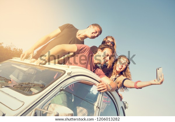 Group of happy people taking a selfie in a car at\
sunset in summer.