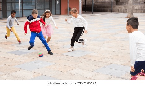 Group of happy schoolchildren playing football together on the street - Powered by Shutterstock