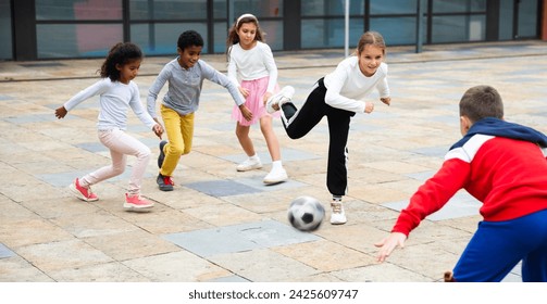 Group of happy schoolchildren playing football together on the street - Powered by Shutterstock