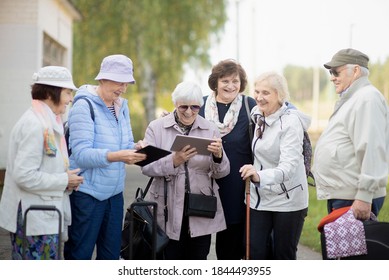 Group Of Happy Senior Elderly People Looking At Digital Map On Traveling Journey During Pandemic. COVID-19 Travel In The New Normal. 