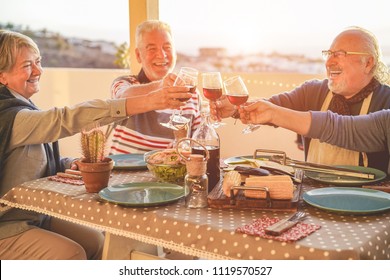 Group Of Happy Senior Friends Cheering At Barbecue Meal In Terrace Outdoor - Mature Old People Drinking Wine At Patio Bbq Dinner - Main Focus On Left Woman Glass - Joyful Elderly Lifestyle Concept