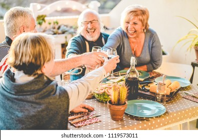 Group Of Happy Senior Friends Cheering At Barbecue Meal In Terrace Outdoor - Mature Old People Drinking Wine At Patio Bbq Dinner - Main Focus On Left Hands Glasses - Joyful Elderly Lifestyle Concept