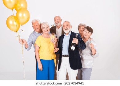 Group of happy senior friends holding yellow balloons and standing in white interior - Shutterstock ID 2027034941