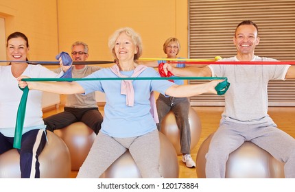 Group Of Happy Senior People Doing Back Training With Exercise Band In Gym