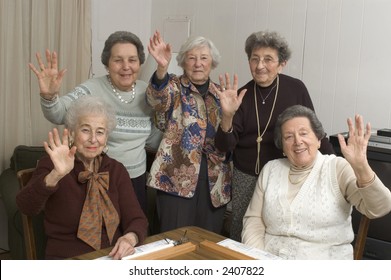 Group Of Happy Senior Women Playing Mah-jong With Friends Waving Hello