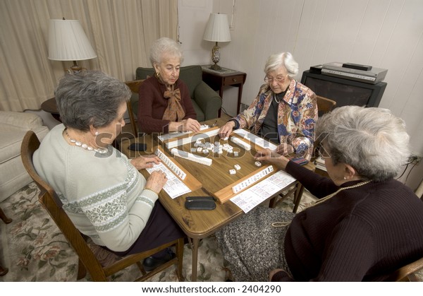 group of happy senior women playing mah-jong with friends