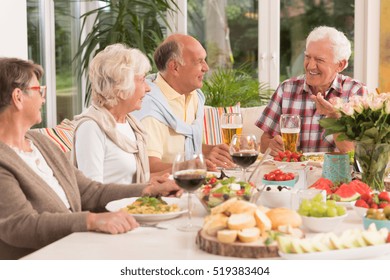 Group Of Happy Seniors Eating A Dinner, Drinking Beer And Wine