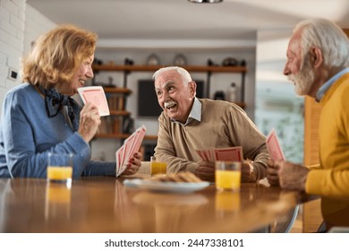 Group of happy seniors having fun while playing cards at home. - Powered by Shutterstock